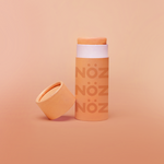 Load image into Gallery viewer, Nöz Sunscreen neon color marmalade on display. A small orange stick with Nöz logo.

